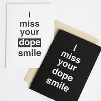 pictured are two greeting cards that read "I miss your dope smile". one card is black with white writing and the other card is white with black writing.